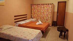 A hotel room with two beds, a wooden headboard, a small table, a stool, and a shower curtain with a geometric pattern. - Pousada e Pizzaria Sol e Alegria (Fortaleza)