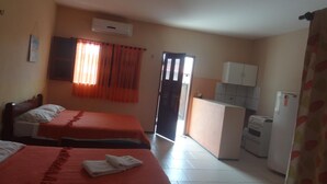Een kamer met twee bedden, een kleine kitchenette en een deur naar een buitenruimte.