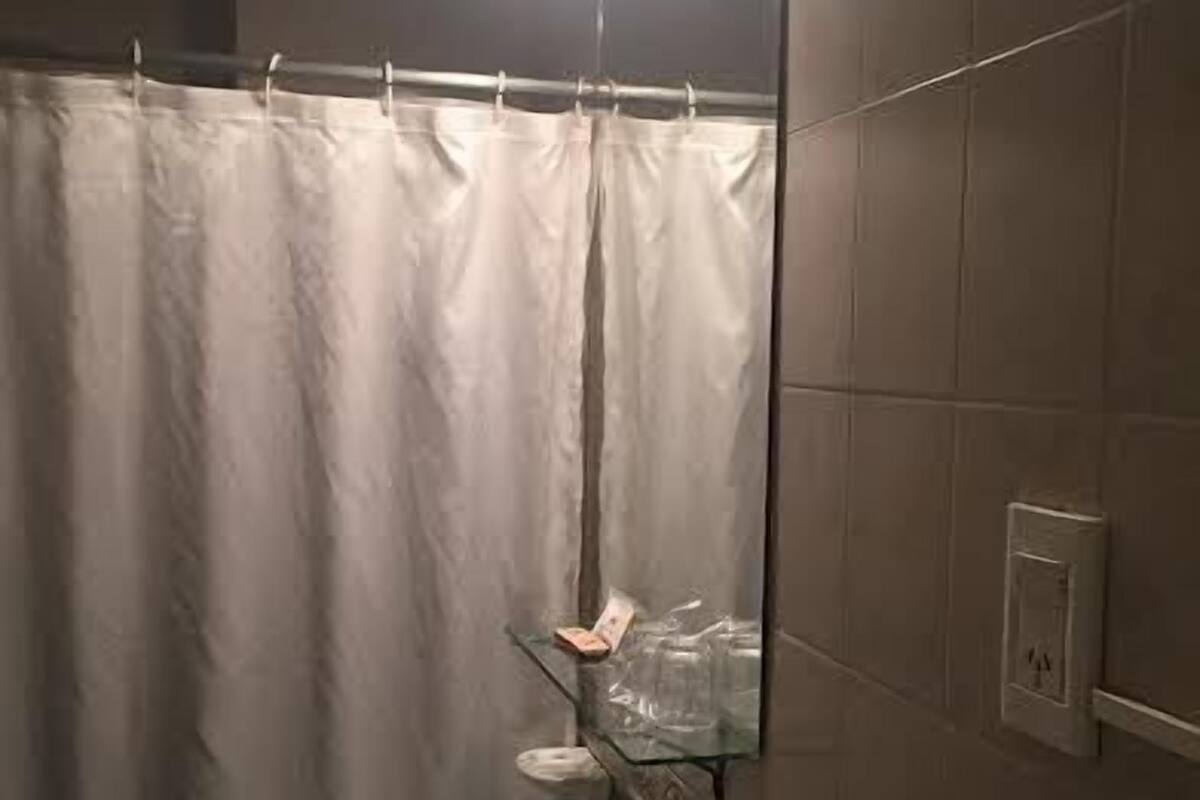 A bathroom with a white sink, a glass shower enclosure, and a mirror with a decorative frame.