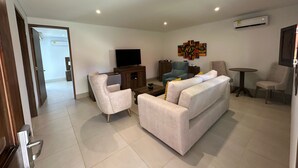 Una sala de estar moderna con un sofá, sillones, un televisor y una mesa de centro.