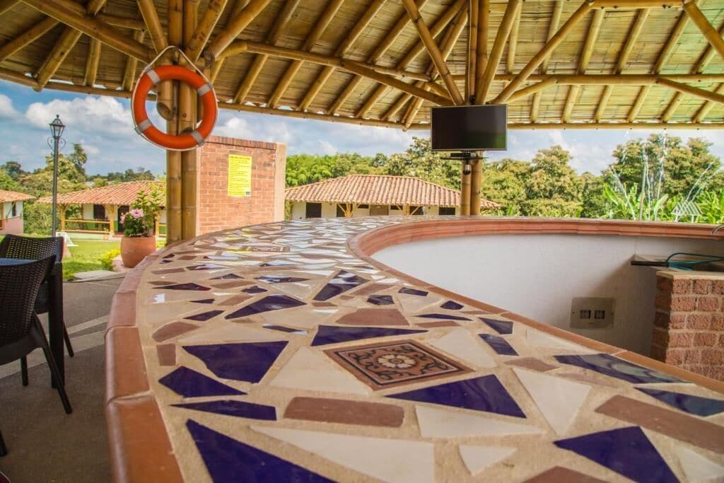 A covered outdoor area with a mosaic floor, a brick wall, and a lifebuoy hanging from a pole.