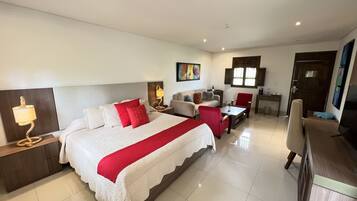 A hotel room with a large bed, a desk, a chair, a TV, and a window.
