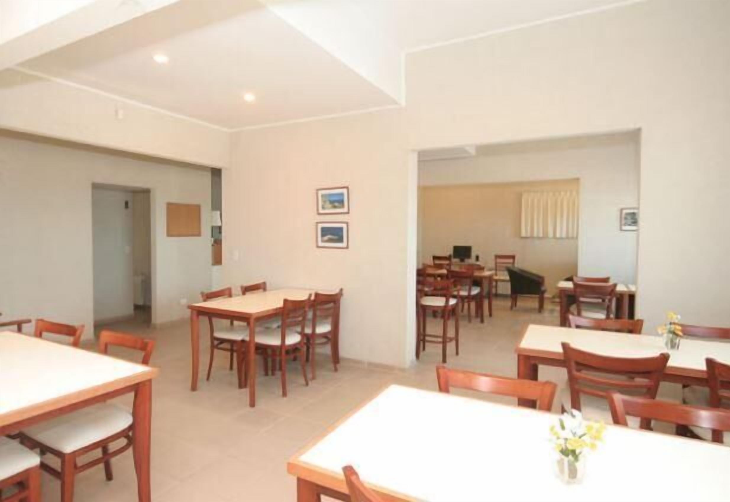 A dining area with multiple tables and chairs, a visible door, and framed pictures on the wall.