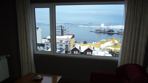 A room with a large window overlooking a harbor, a wooden table, and a red polka-dotted chair. - Hotel Tierra del Fuego (Ushuaia)