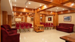 A conference room with rows of red chairs, a wooden table, and a red sofa. - Hotel Tierra del Fuego (Ushuaia)