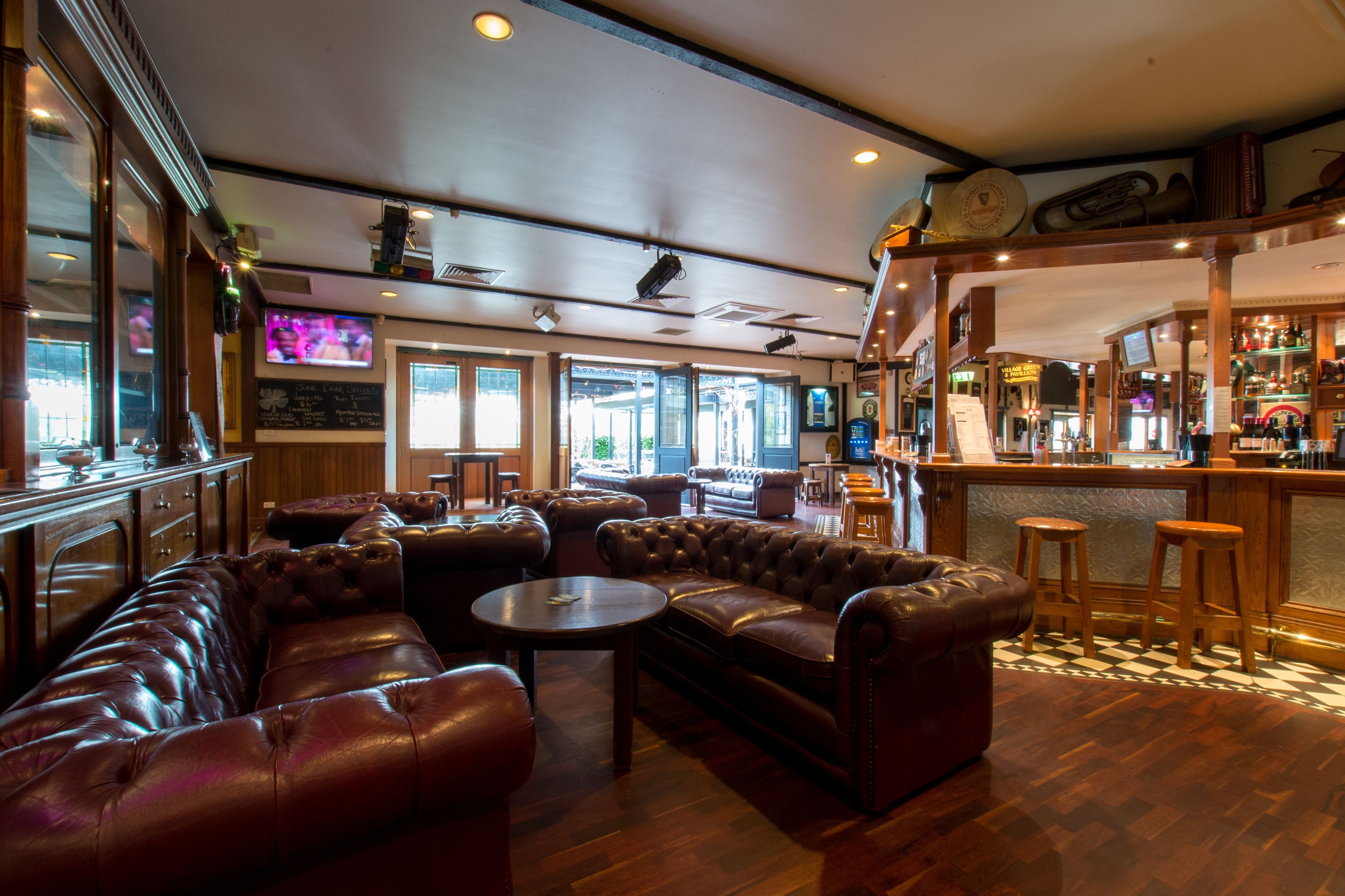 A bar area with leather seating, a bar counter, and a television screen.