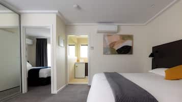 Ein Hotelzimmer mit einem Bett, einem Schreibtisch, einem Spiegel und einer Klimaanlage.