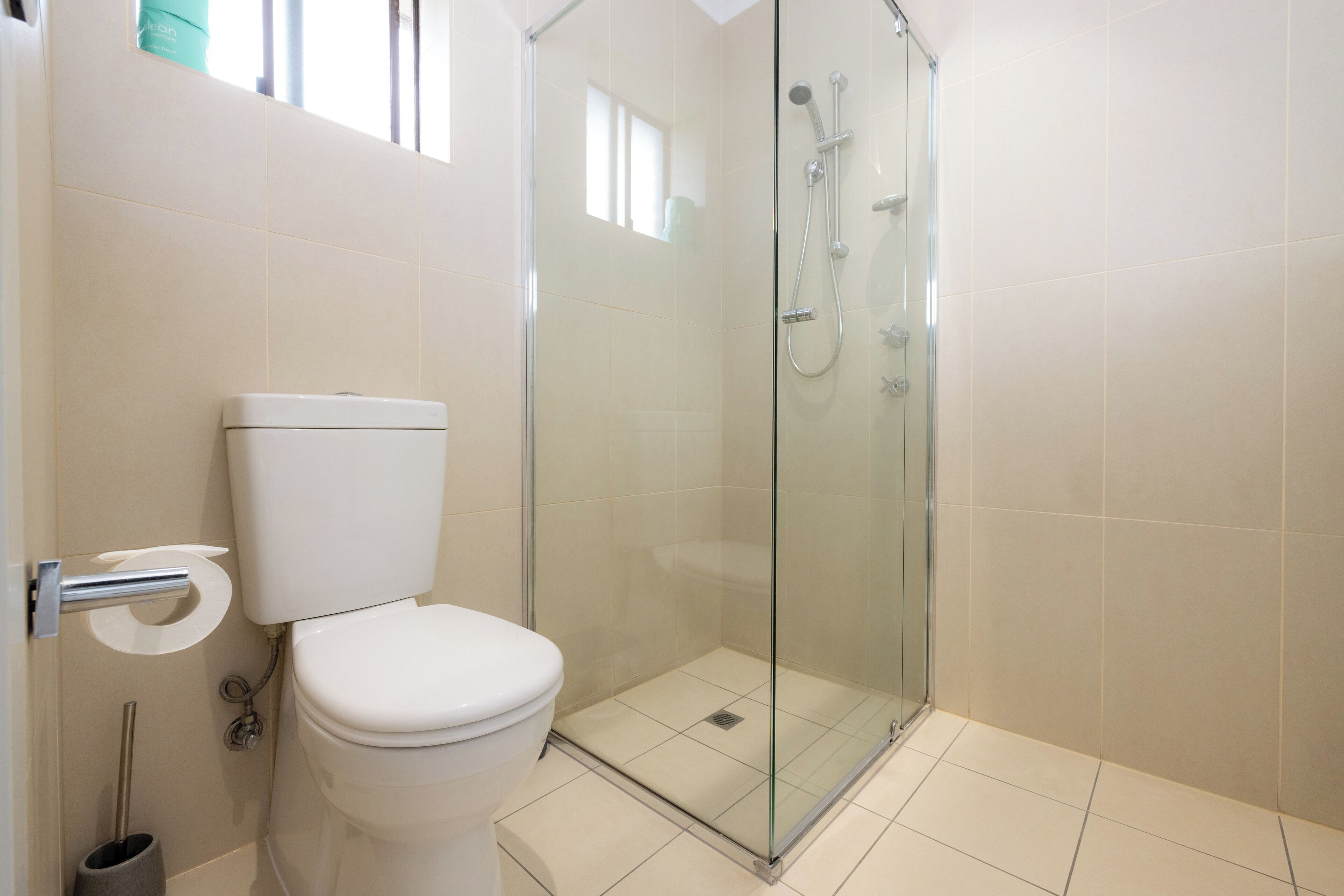 Ein Badezimmer mit Toilette, einer Duschkabine und einem Toilettenpapierhalter.