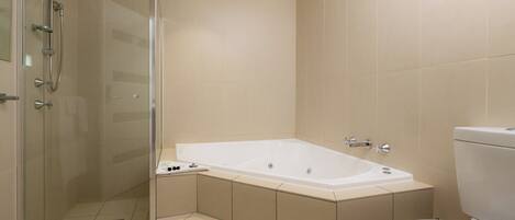 A bathroom with a glass-enclosed shower, a freestanding bathtub, and a toilet.