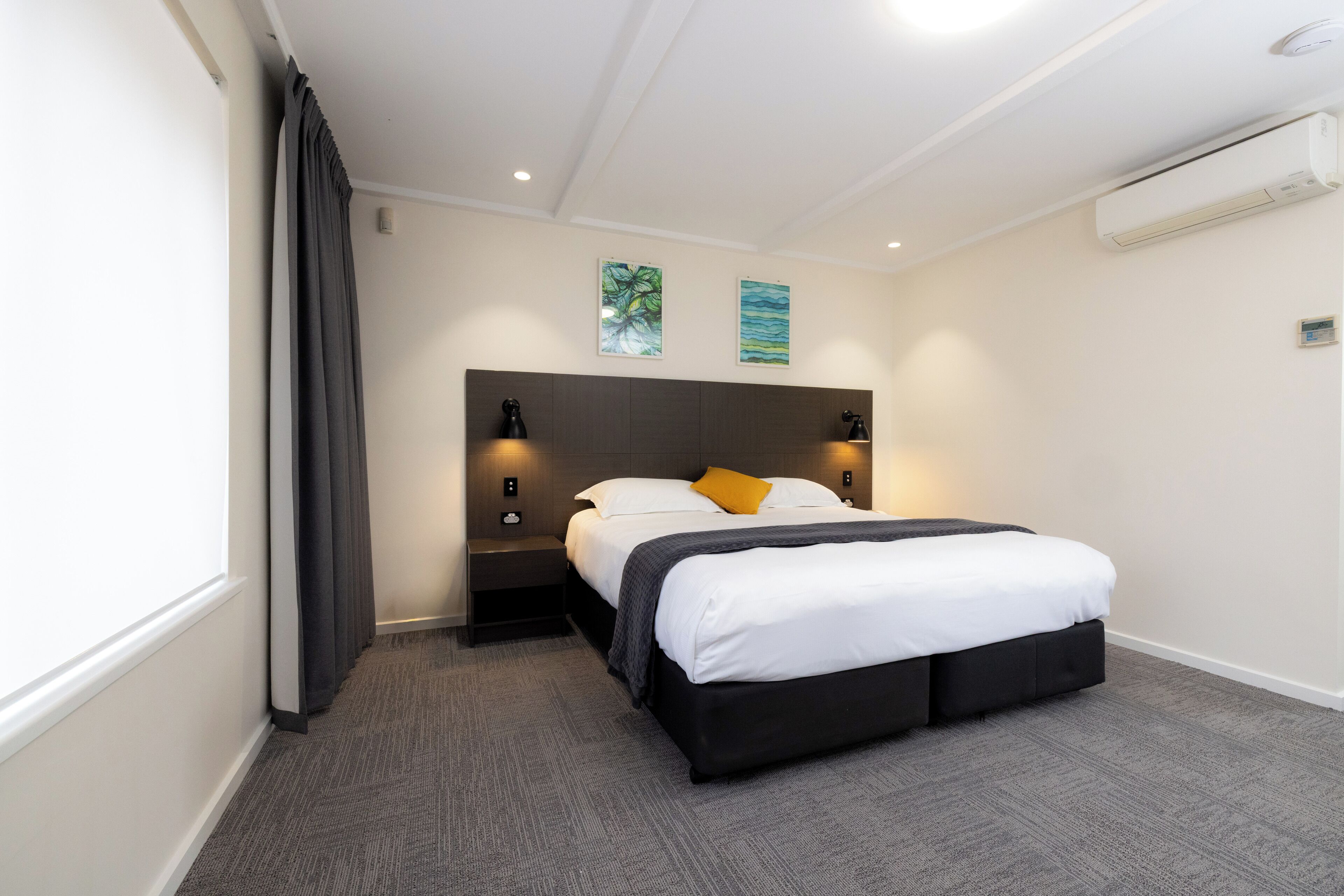 A hotel room with a bed, nightstands, and wall-mounted lamps.