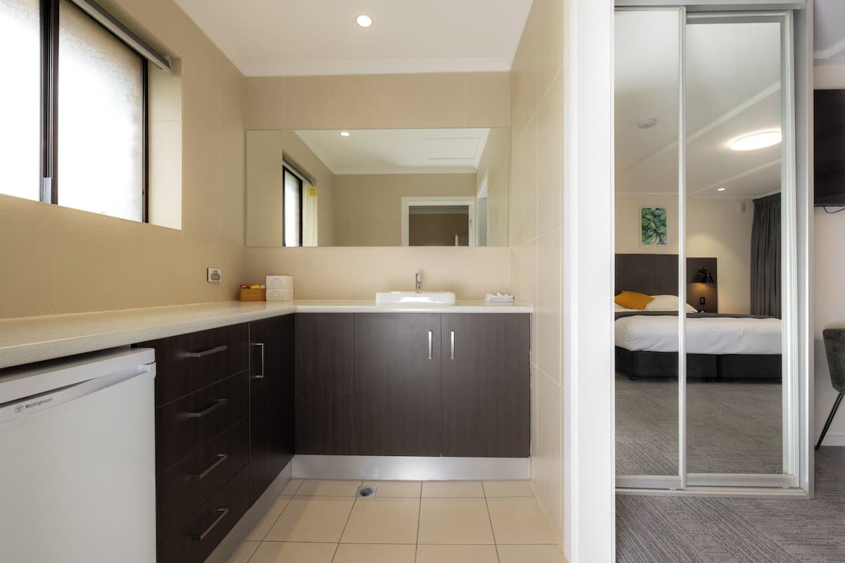A modern bathroom with a sink, dark cabinets, and a shower area.