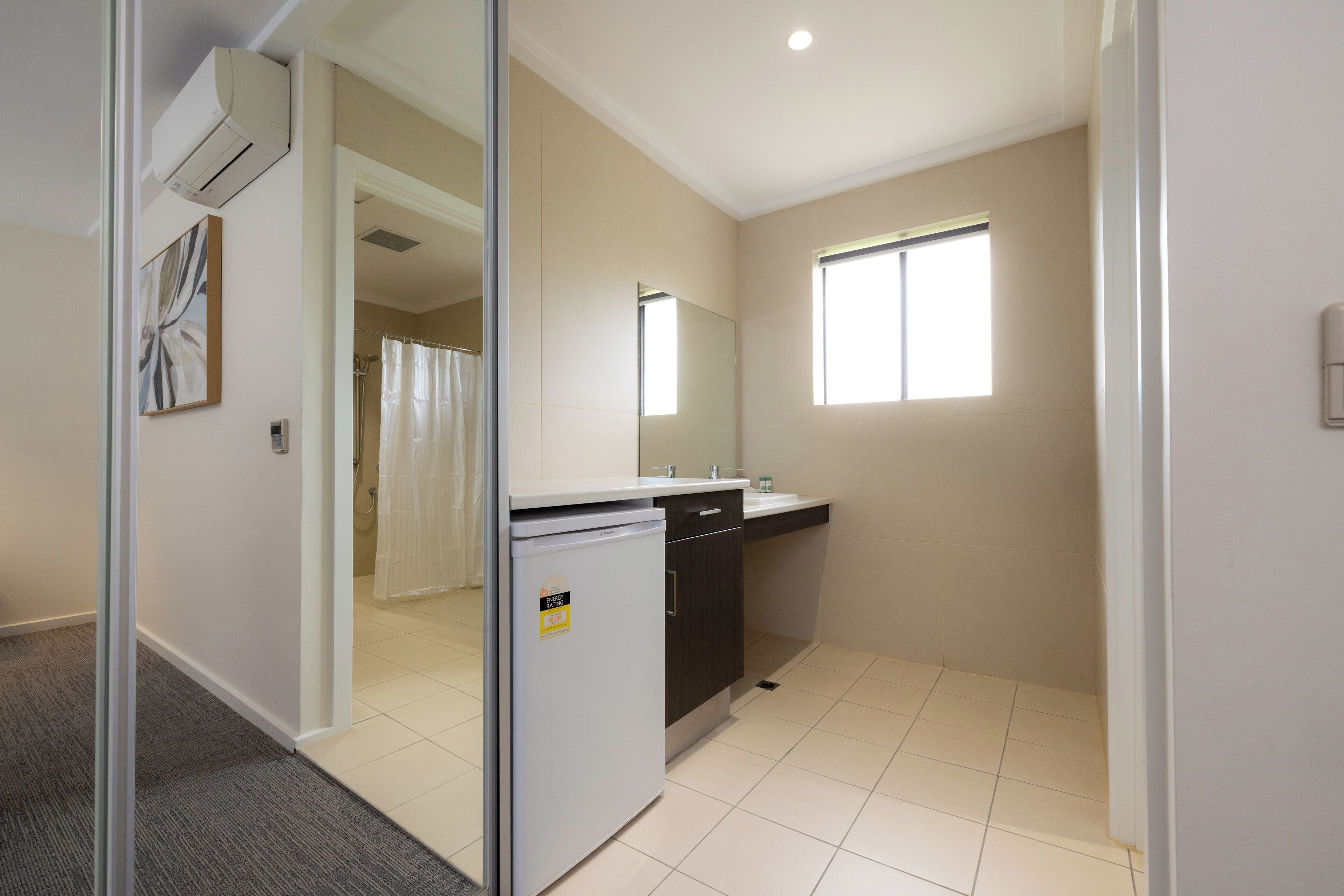 A compact kitchen with a refrigerator, a sink, and a window providing natural light.