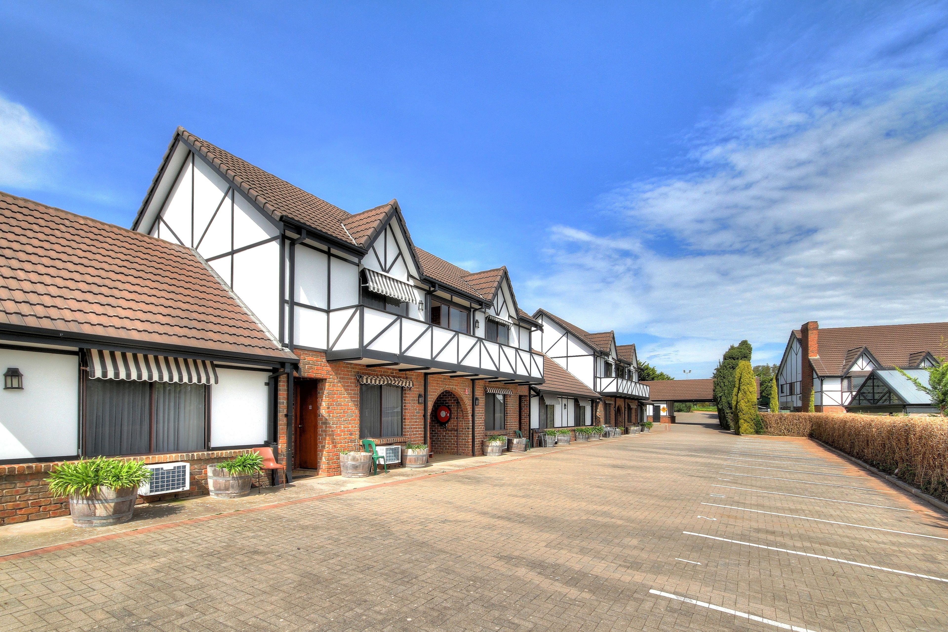A row of traditional half-timbered houses with a paved parking area in front.