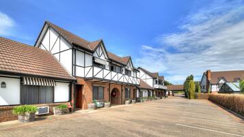 A row of traditional half-timbered houses with a paved parking area in front.