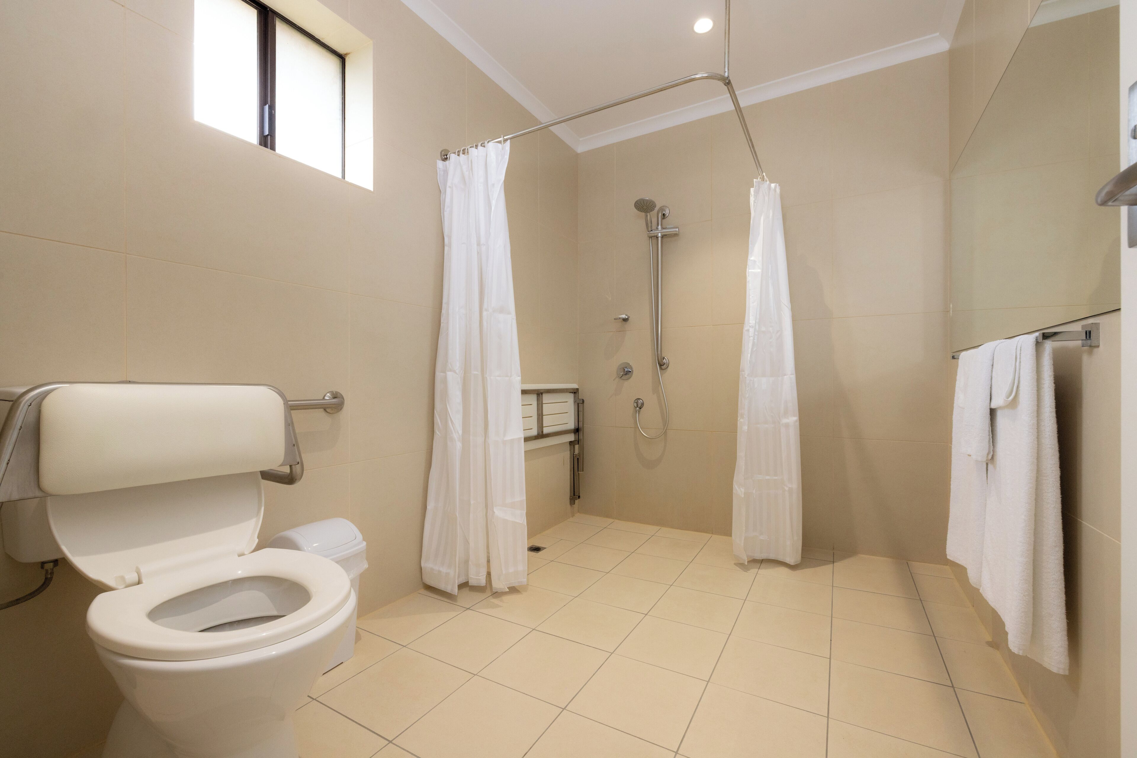 A modern bathroom with a toilet, shower, and a window.