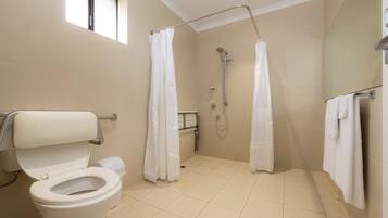 A modern bathroom with a toilet, shower, and a window.