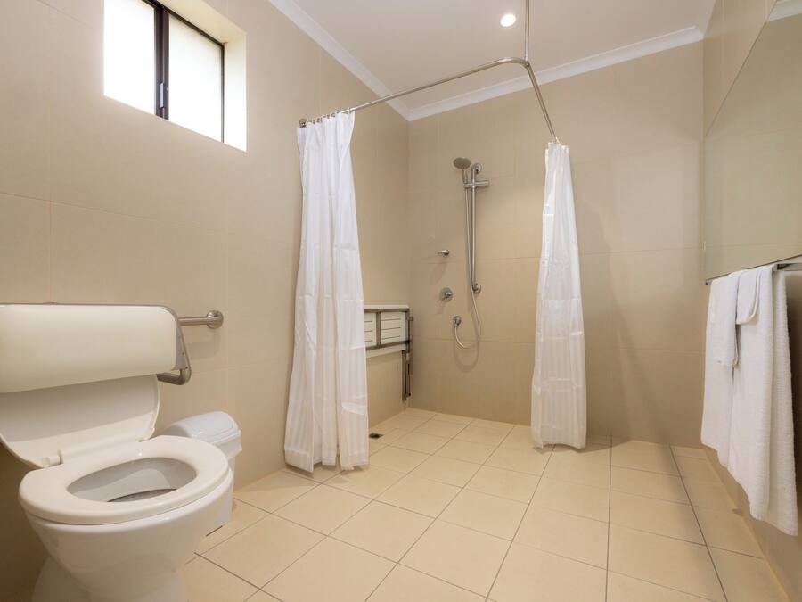 A modern bathroom with a toilet, shower, and a window.