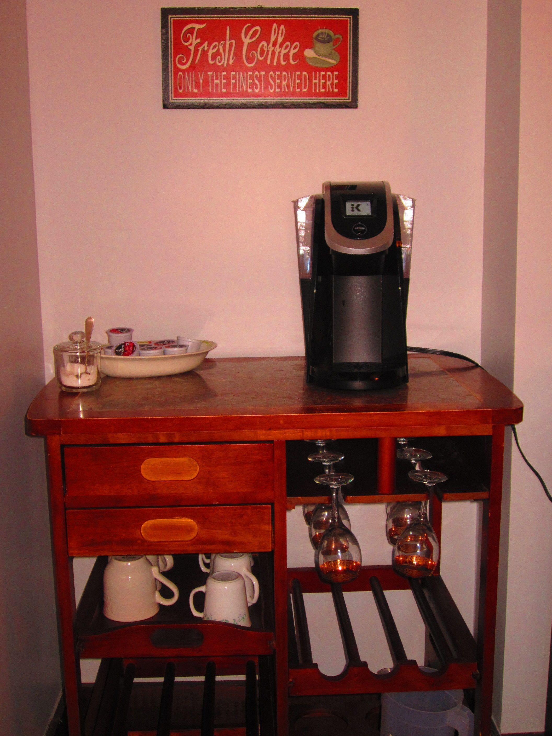 Una estación de café con cafetera, tazas y un cartel que dice 'Fresh Coffee Only the Finest Served Here'.