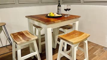 A dining table with a wooden top, two white chairs, and a bottle of wine on the table.