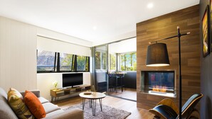 A modern living room with a sofa, TV, fireplace, and a dining area with chairs and a table.