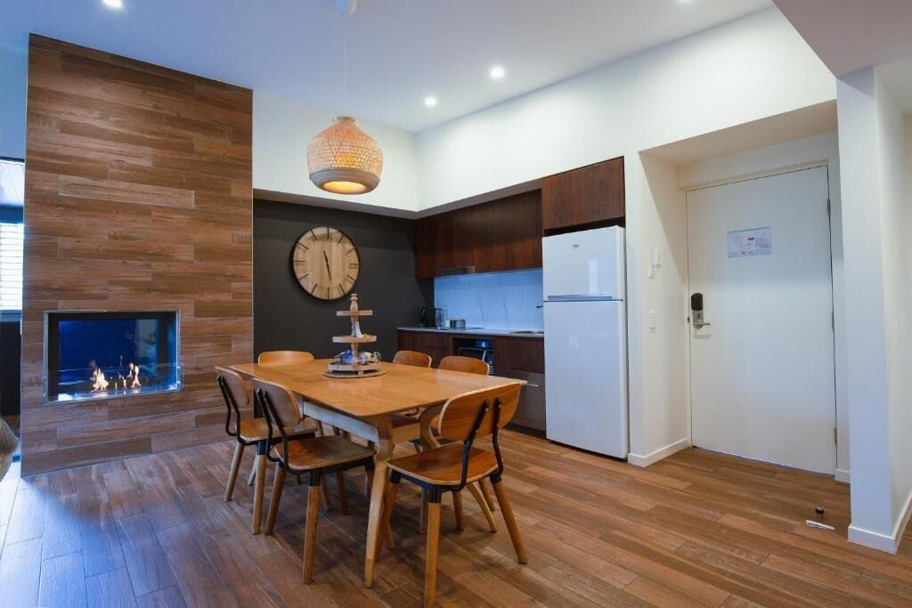 Una cocina moderna con comedor, suelo de madera y chimenea empotrada.