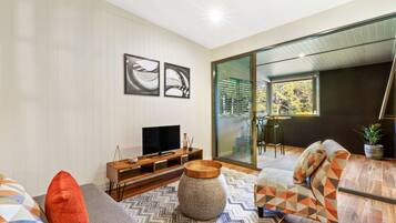 A modern living room with a television, sofa, and a large window.