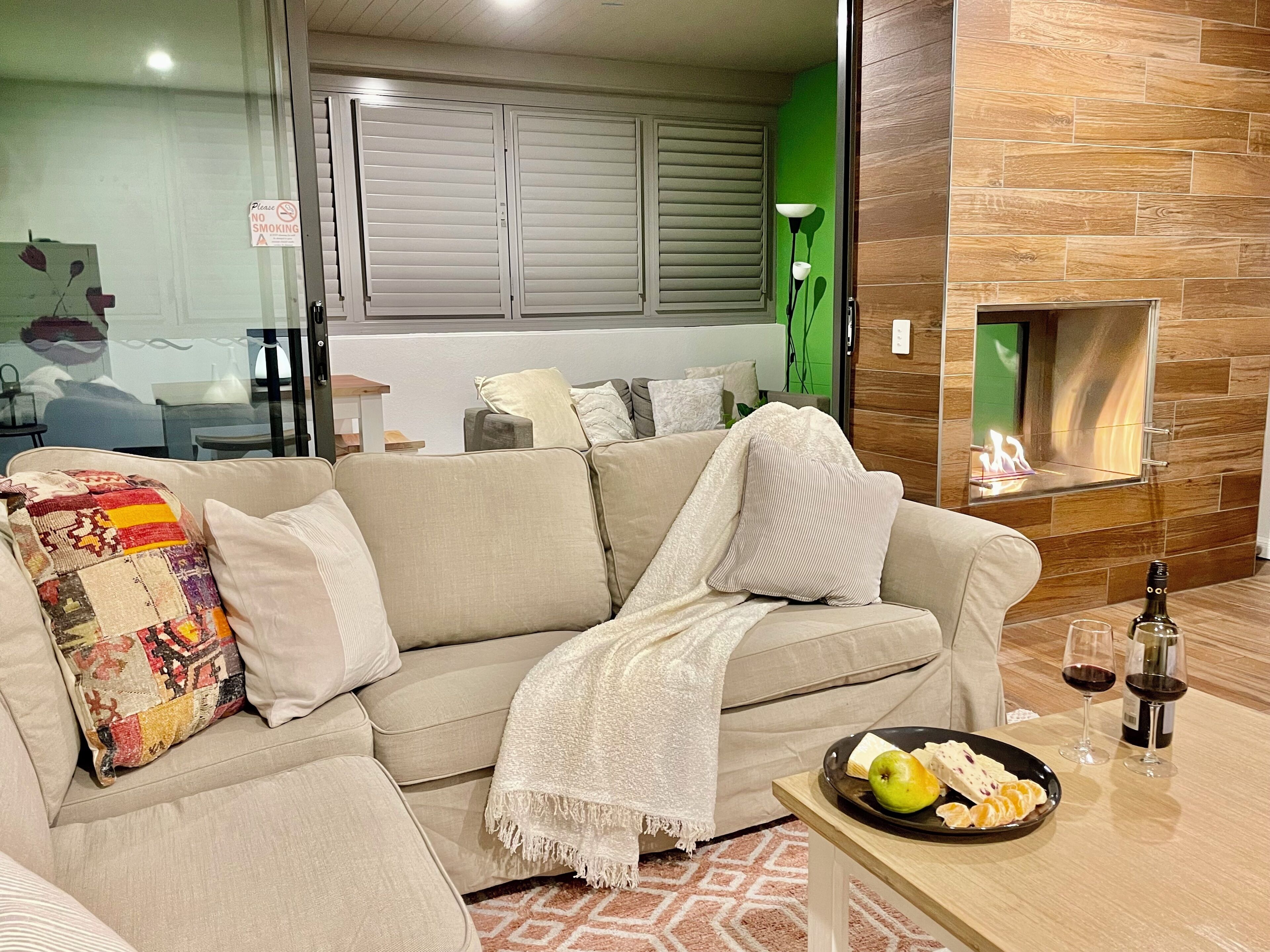 A living room with a beige sofa, a fireplace, and a table with snacks and drinks.