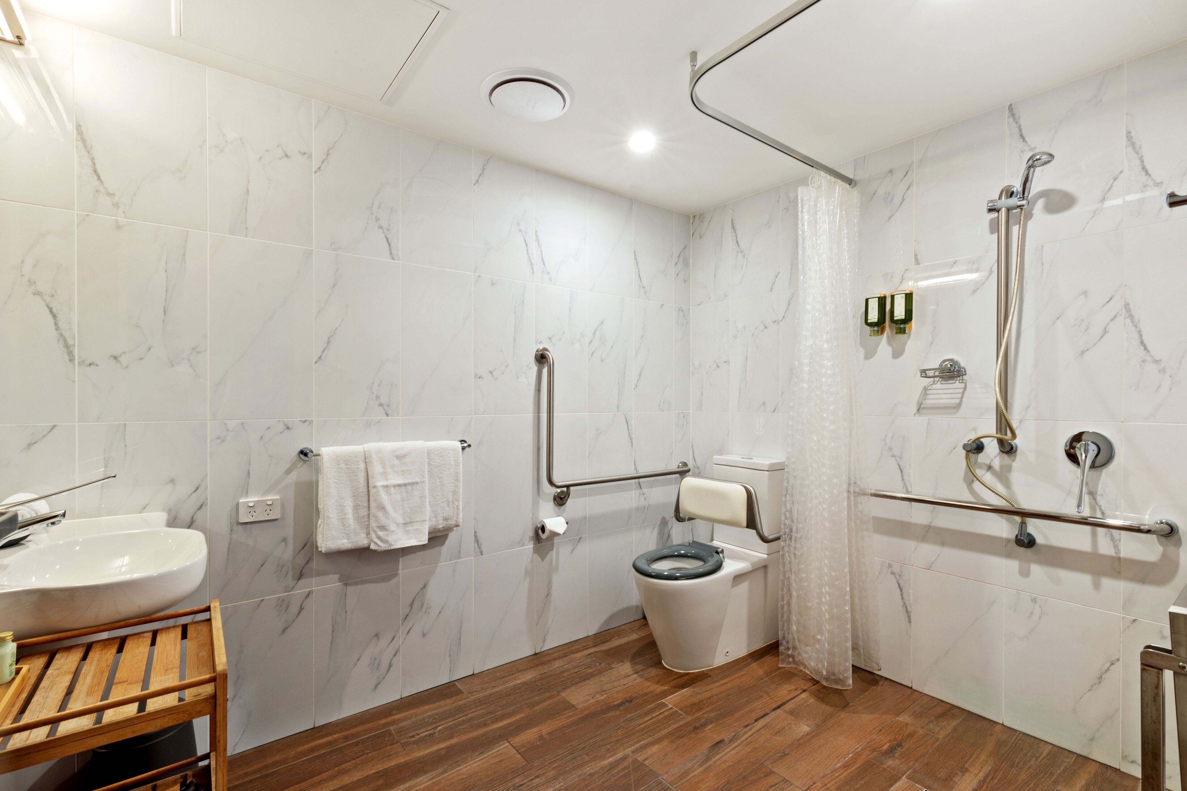 A modern bathroom with a marble floor, a sink, a toilet, and a shower area.