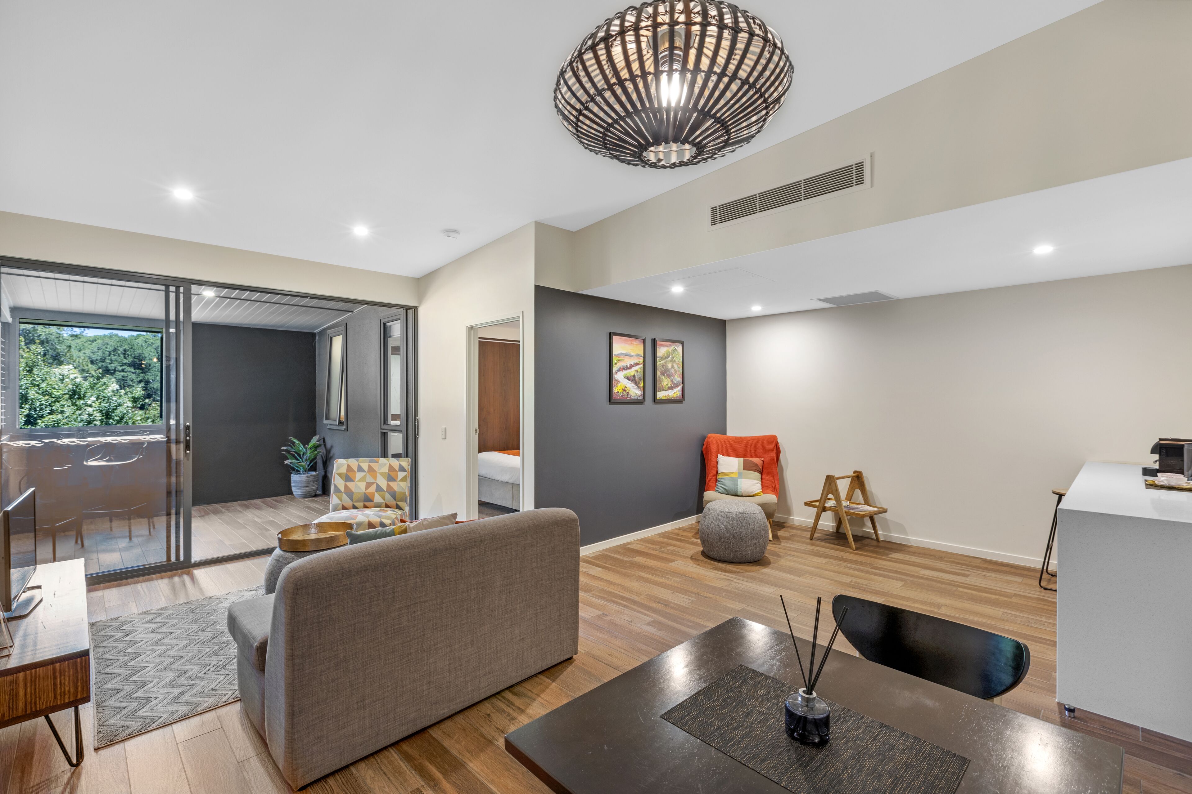 Una sala de estar moderna con un sofá, una mesa de centro y un comedor. Hay un ventanal que ofrece vistas al exterior.
