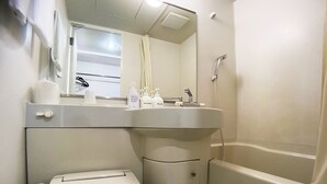 Un baño con inodoro, lavamanos con jabón de manos y ducha.