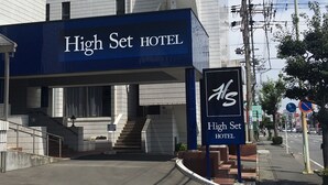 Exterior del High Set Hotel, con una entrada destacada y una escalera que conduce a la recepción.
