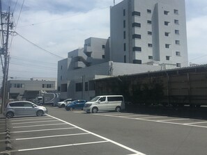 A parking lot with several cars and a large building in the background. - High Set HOTEL Shizuoka Inter (Shizuoka)