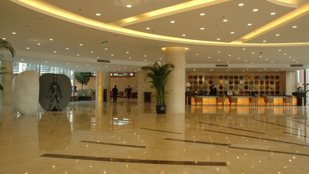 A spacious lobby with a polished floor, a reception desk, and a large decorative sculpture. - Century Hotel Taicang (Suzhou)