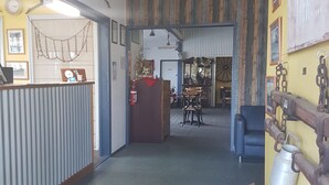 A lobby with a reception desk, a dining area with chairs and tables, and a blue sofa. - Monto Colonial Motor Inn (Monto)