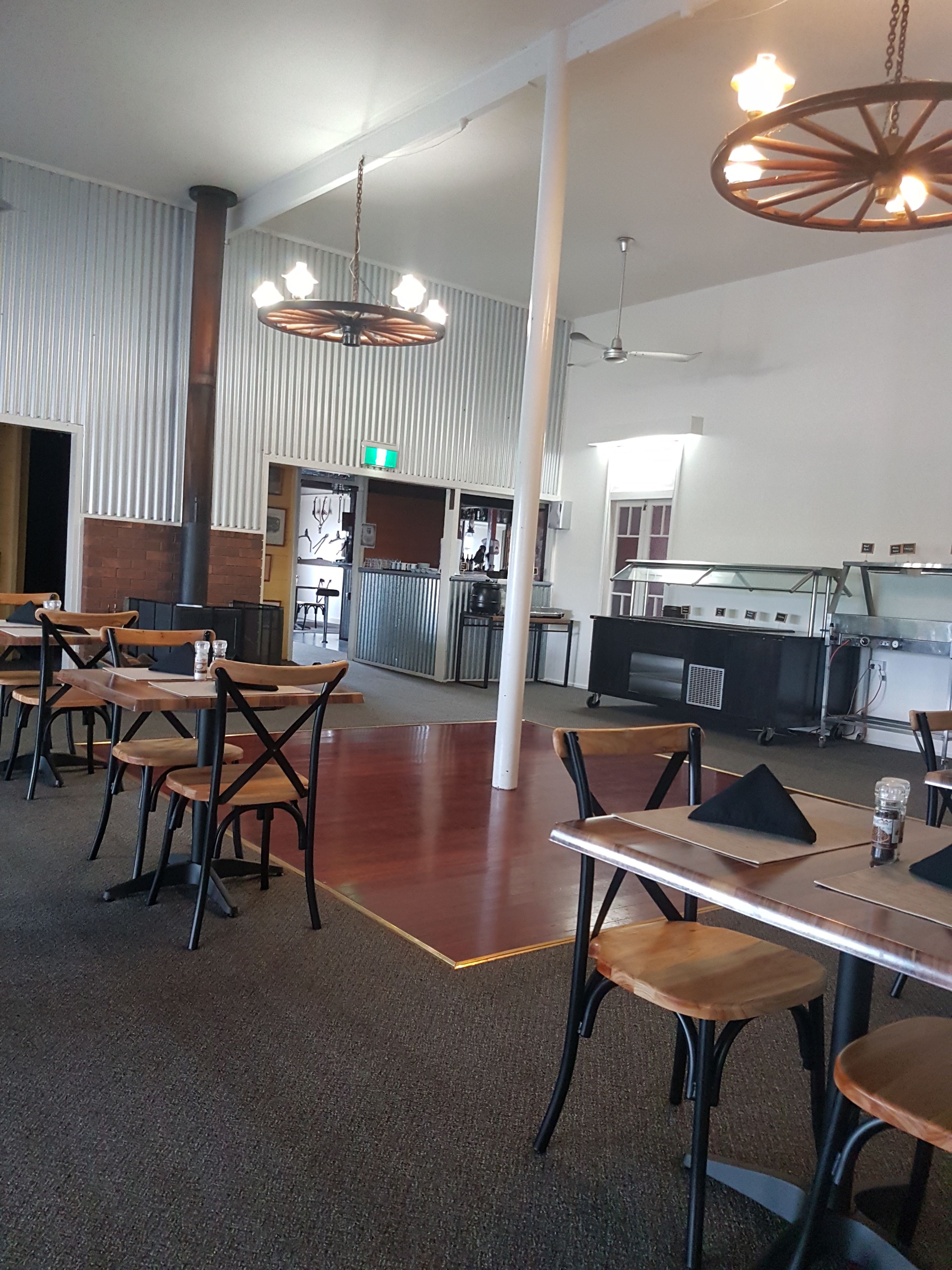 A spacious restaurant with high ceilings, exposed brick walls, and a variety of seating options including tables and chairs.