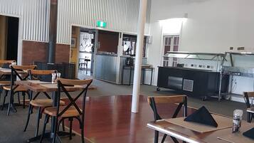 A spacious restaurant with high ceilings, exposed brick walls, and a variety of seating options including tables and chairs.