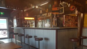 A bar area with a counter, stools, and various bottles and decorations. - Monto Colonial Motor Inn (Monto)