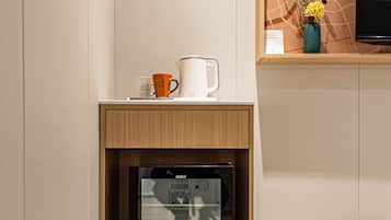 Una kitchenette compacta con microondas, cafetera y un pequeño estante con adornos.