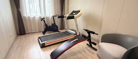 A home gym with a treadmill, stationary bike, and elliptical machine.