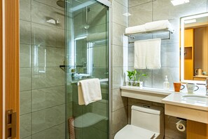 A modern bathroom with a glass shower enclosure, a toilet, a sink with a mirror, and a towel rack. - Shanghai JOYFUL YARD Hotel (Shanghai)