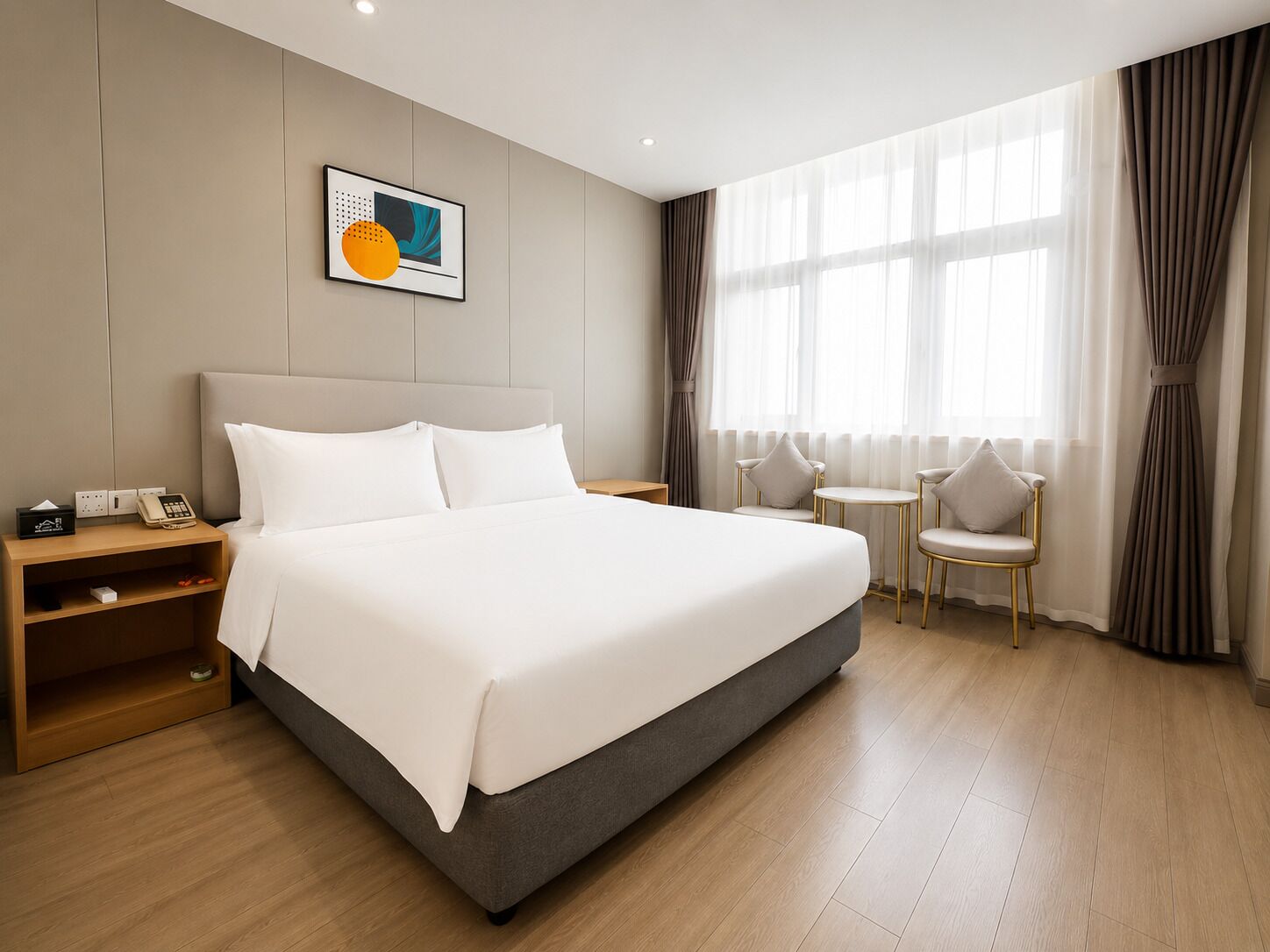 Une chambre d’hôtel avec un grand lit, des tables de chevet, une petite table ronde et des chaises.