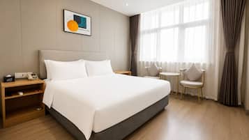 Une chambre d’hôtel avec un grand lit, des tables de chevet, une petite table ronde et des chaises.