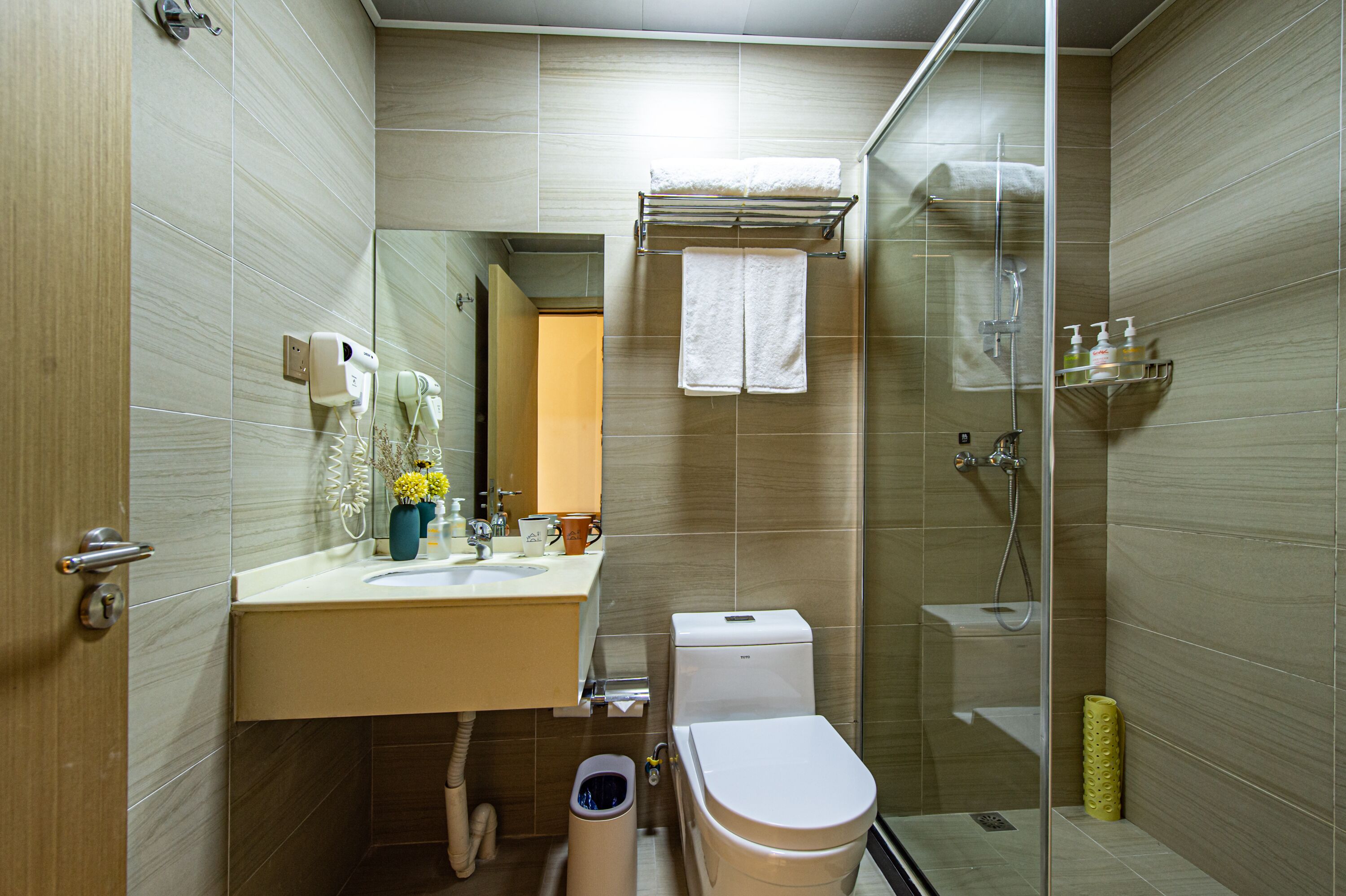 A modern bathroom with a glass shower enclosure, a toilet, and a sink with a towel rack above it.