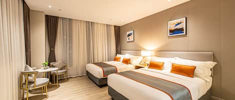 A hotel room with two beds, a small table with chairs, and a window with curtains.