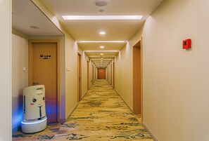A hotel hallway with a carpeted floor, wooden doors, and a water dispenser on the left.