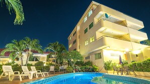 A swimming pool with lounge chairs and a building with balconies.