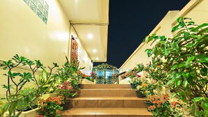 A staircase with potted plants on either side, leading to a brightly lit entrance. - Butterfly Garden Boutique Residence by Frasier (Pattaya)