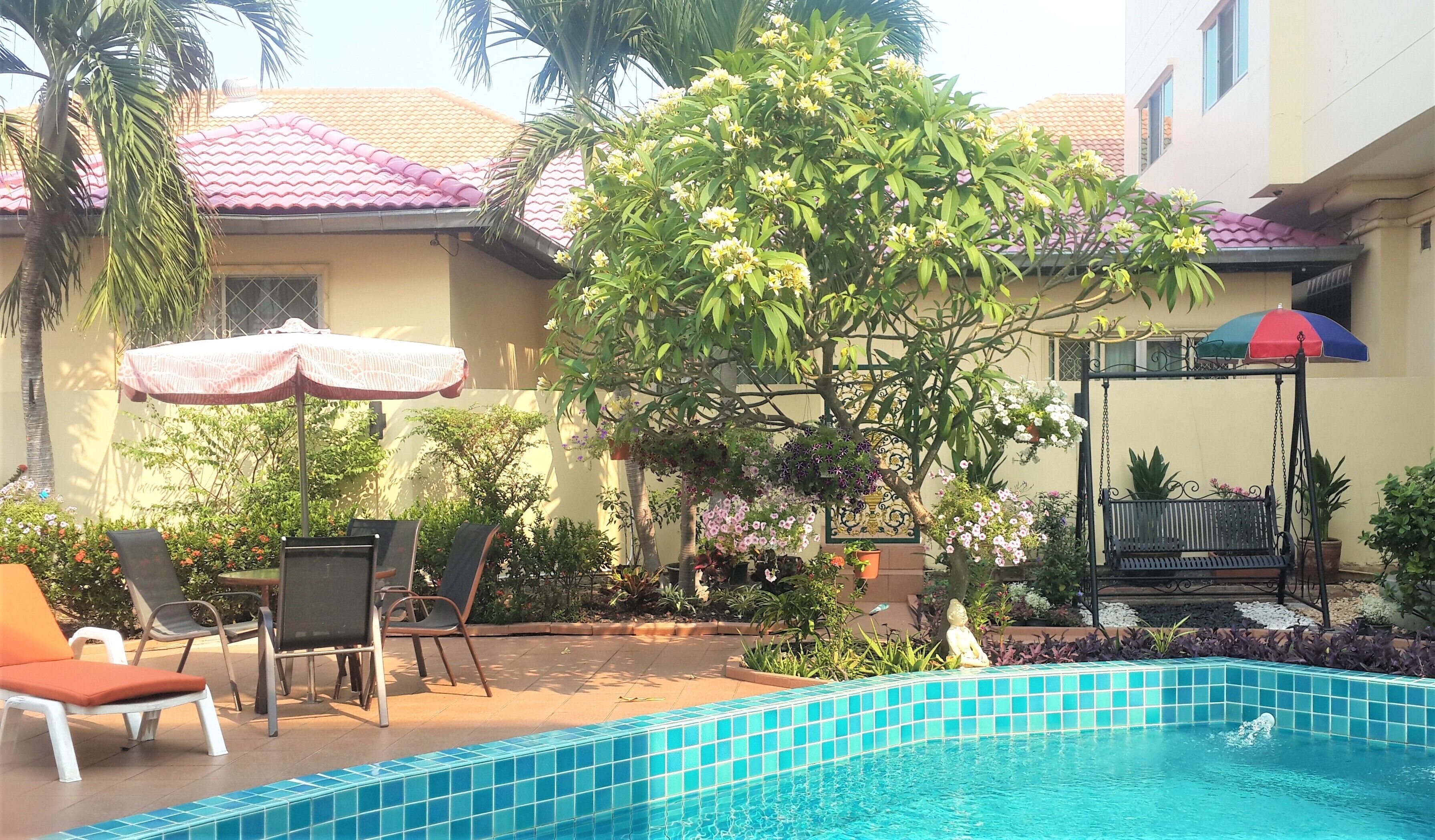 A swimming pool with a tiled edge, surrounded by lounge chairs and a table.