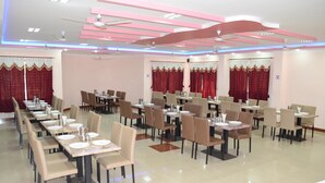 A spacious dining area with multiple tables and chairs, ceiling fans, and decorative lighting. - KSTDC Hotel Mayura Chalukya Badami (Badami)