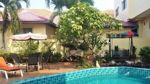 A pool area with a tiled edge, lounge chairs, and a bench.